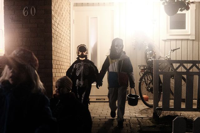 a photograph of a group of children in costumes walking out of a house
