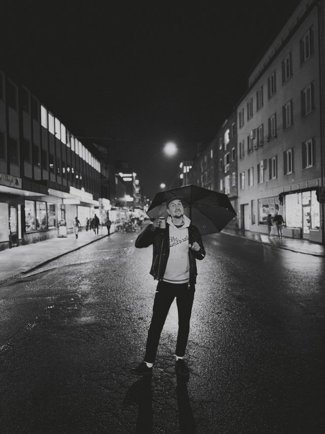 a photograph of a man holding an umbrella in the middle of a city street