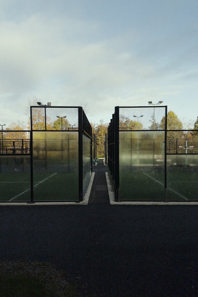 a photograph of a tennis court with a fenced in area with a tennis court