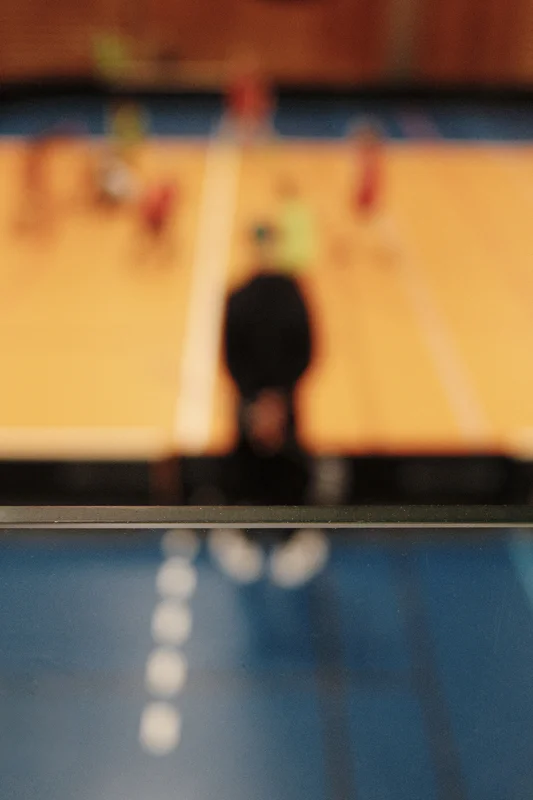 Blurred view of a person standing behind a glass pane, with indoor background lights.
