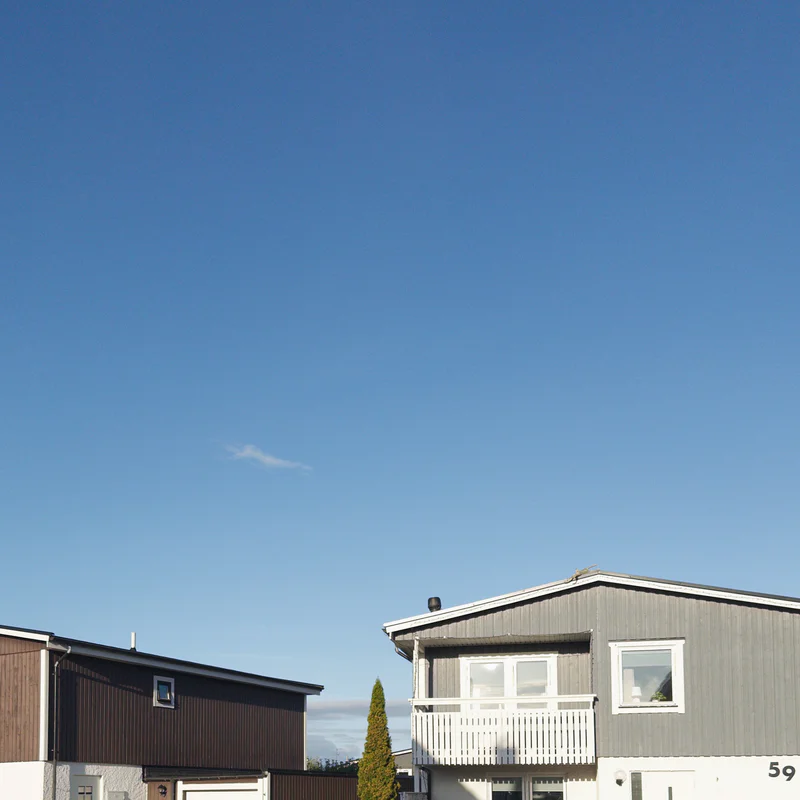 Two small houses with a wooden fence and clear blue sky in the background.