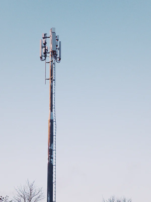 Tall metal cellular tower with antennas against a clear blue sky