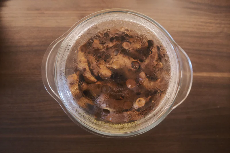 Clear glass filled with food on a wooden table.