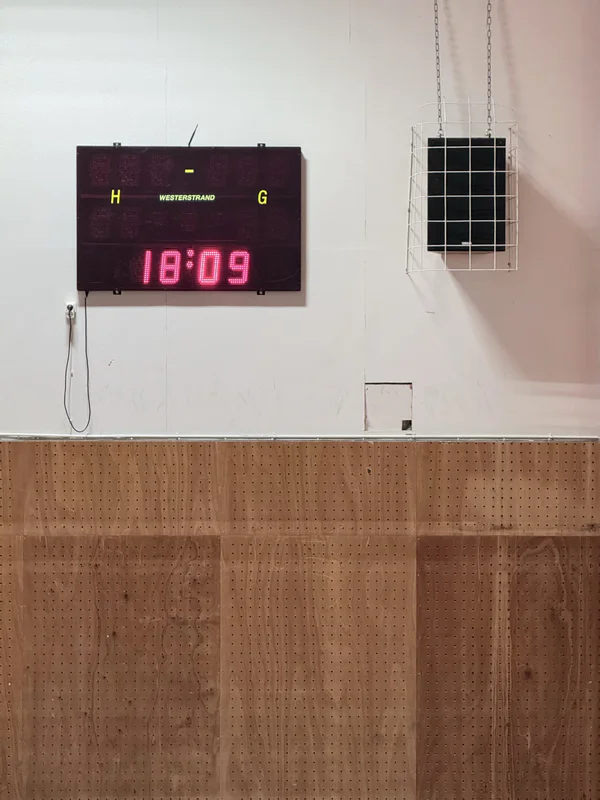 Indoor court wall with a digital score display showing “18:09” and two colored letters.