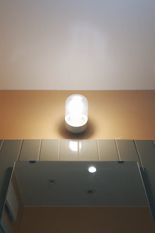 Bright ceiling spotlight above a glass-top fixture with small blue labels and recessed lights.