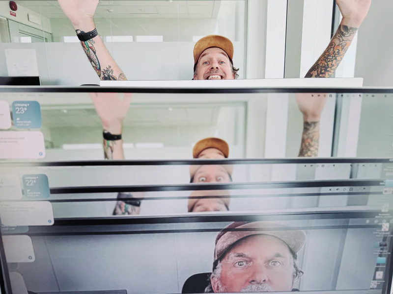 Smiling man wearing a tan cap and tattoos behind a screen where he appears repeatedly in a collage.