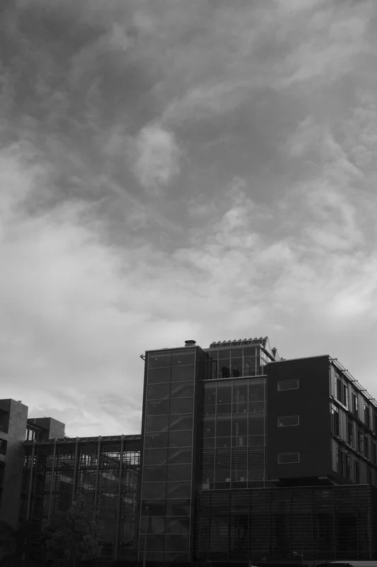 Black and gray city buildings with a cloudy sky overhead.