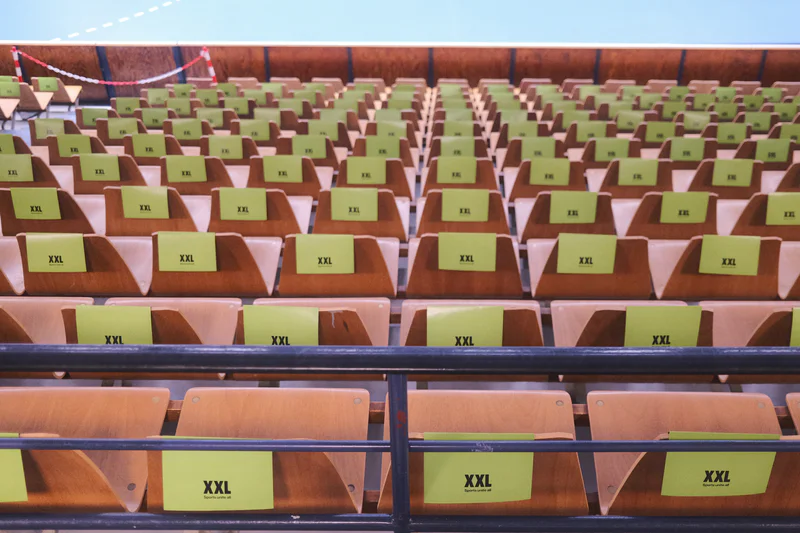 Rows of empty seats with green labels, viewed from above across two rail sections.