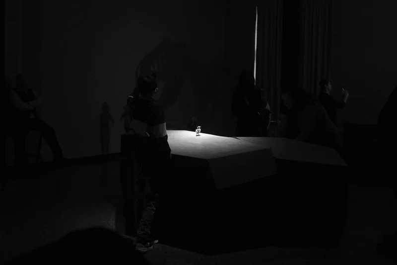 Dark room with several people standing around a white-lit platform.