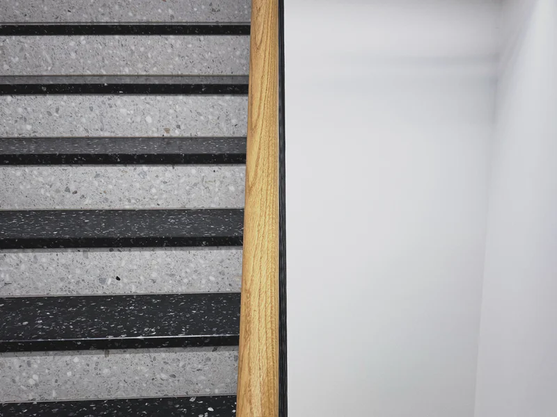 Grey stone steps with dark edges and a vertical wooden handrail.