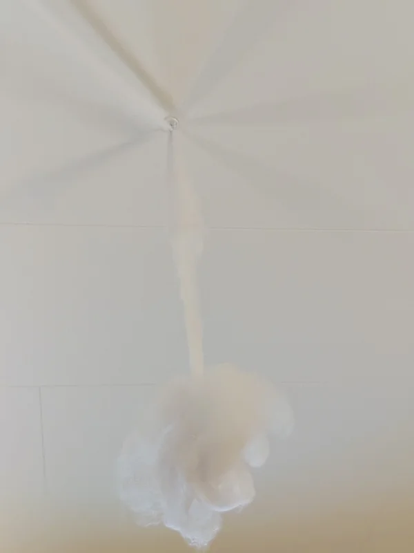 Close-up of a white ceiling corner with a faint circular stain and soft shadow beneath.