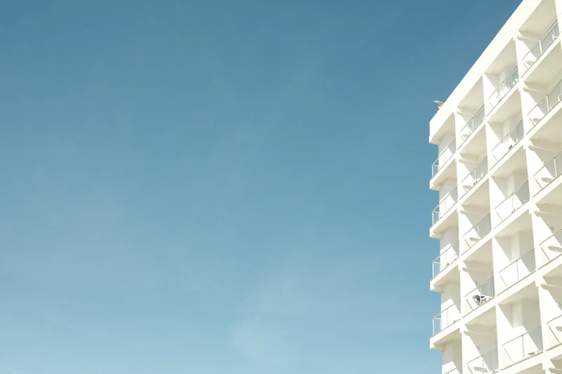 Blue sky with the upper corner and balconies of a white hotel building on the right.