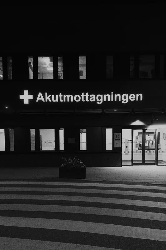 Night view of a building entrance with the illuminated sign “Akutmottagningen.”