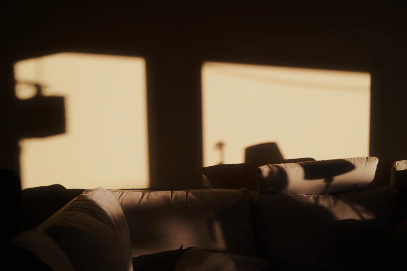 Sofa cushions in a dim room with bright daylight coming through two windows.